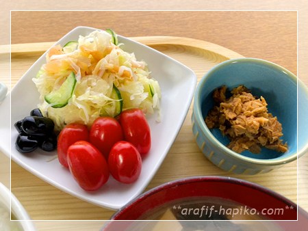 千切りキャベツ・にんじん・たまねぎ・セロリ・きゅうり・ハム・かにかまのコールスロー、ミニトマト、黒豆、マグロの佃煮の小鉢